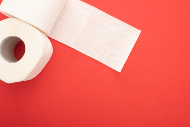 Вид сверху белых рулонов туалетной бумаги на красном фоне с копировальным пространством - Фото, изображение