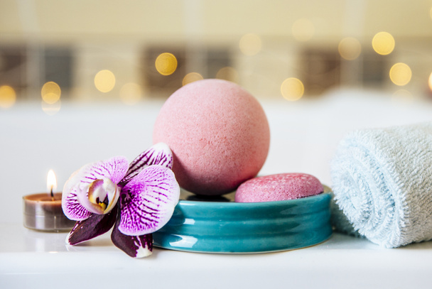 Close up of pink bath ball with orchid flower, scented candle on blue ceramic tray in bath room. - Photo, Image
