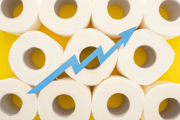 vue du dessus de la flèche bleue sur des rouleaux de papier toilette blanc sur fond jaune
 - Photo, image