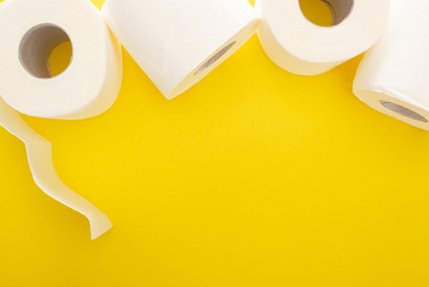 top view of white toilet paper rolls on yellow background with copy space - Fotó, kép