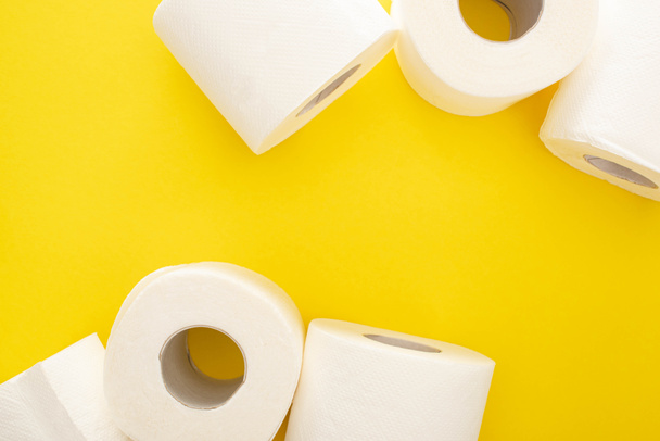 Верхний вид рулонов белой туалетной бумаги на желтом фоне с копировальным пространством - Фото, изображение