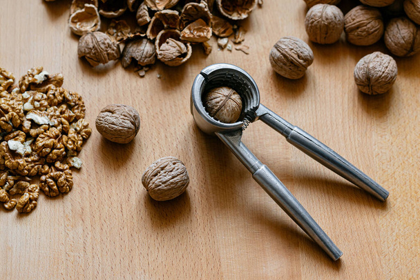 walnuts and nutcracker on wooden background - Foto, imagen
