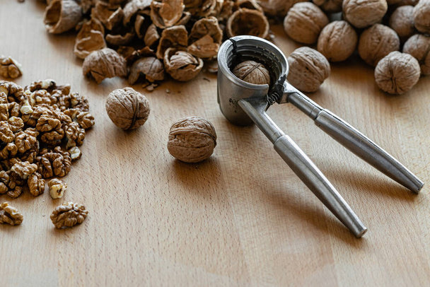 walnuts and nutcracker on wooden background - Fotó, kép