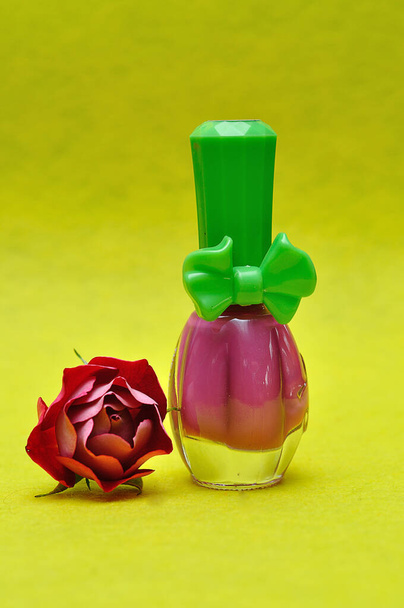Бутылка розового лака для ногтей с красной розой
 - Фото, изображение