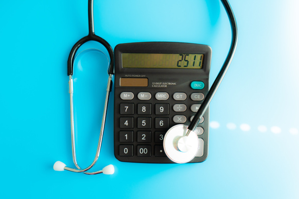 Calculator and stethoscope on financial statement concept for finance health check or cost of healthcare - Photo, Image