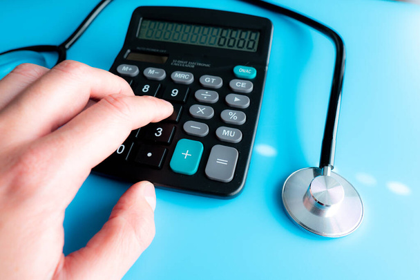 Calculadora y estetoscopio sobre concepto de estado financiero para chequeo financiero o costo de atención médica
 - Foto, imagen