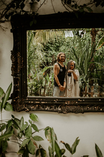 encantadora pareja haciendo foto en el espejo en palmeras fondo
  - Foto, imagen