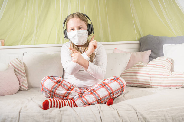 Girl listening music during quarantine in the room on the bed. - Valokuva, kuva