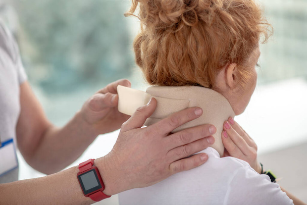Male physiotherapist hands fixing neck bandage on female patient - Foto, Imagen
