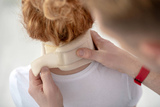 Male physiotherapist hands fixing neck bandage on female patient - Foto, afbeelding