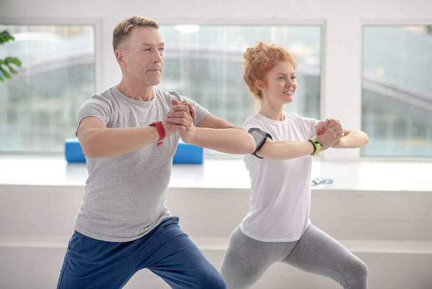 Female patient and male physiotherapist lunging together, smiling - Fotografie, Obrázek