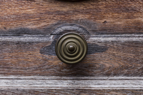 крупним планом ручка дерев'яних дверей, ручка кругла бронза і має креслення концентричних кіл
 - Фото, зображення