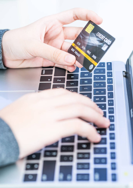 オンライン決済を行う女性の手の閉じる,女性の手はクレジットカードを保持し、オンラインショッピングのためのラップトップを使用して - 写真・画像