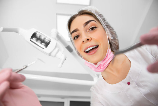 La vue à la première personne du patient à l'examen par le dentiste se trouve dans le fauteuil dentaire. Médecin Chirurgien dentaire examine une cavité buccale à l'aide d'outils somatologiques
. - Photo, image