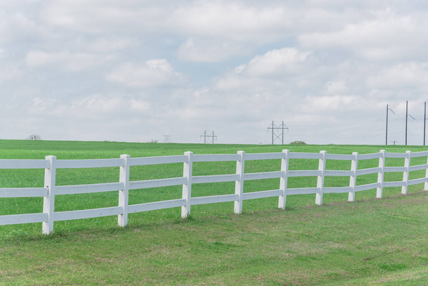 Langer hölzerner weißer Zaun zur horizontalen Linie im wolkenblauen Himmel auf einem Farmland in Ennis, Texas, USA - Foto, Bild