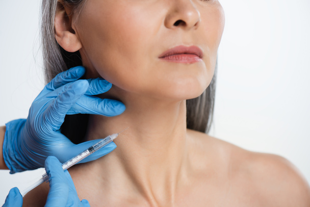 cropped view of naked woman and doctor in latex gloves holding syringe with beauty injection isolated on grey - Foto, afbeelding