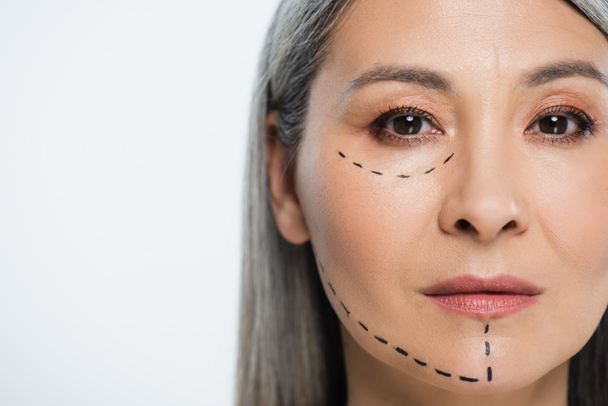 Ασιάτισσα γυναίκα με πλαστικές χειρουργικές γραμμές στο πρόσωπο απομονωμένη σε γκρι  - Φωτογραφία, εικόνα