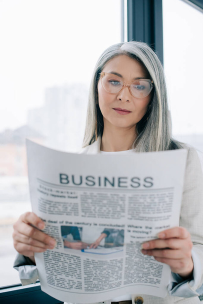 confident asian businesswoman reading business newspaper in office - Fotoğraf, Görsel