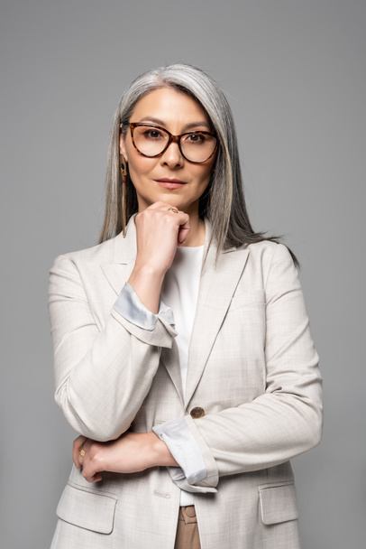 nachdenkliche asiatische Geschäftsfrau mit Brille isoliert auf grau - Foto, Bild