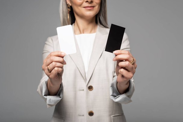 καλλιεργούμενη άποψη της γυναίκας επιχειρηματία που κατέχει επαγγελματικές κάρτες που απομονώνονται σε γκρι - Φωτογραφία, εικόνα