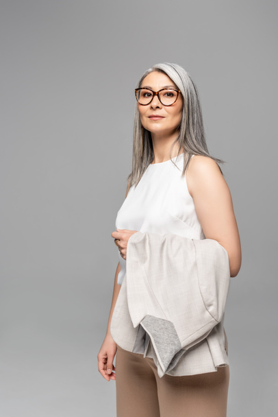 confident asian businesswoman in eyeglasses isolated on grey - 写真・画像