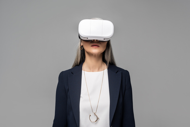 vonzó üzletasszony használ virtuális valóság headset elszigetelt szürke - Fotó, kép