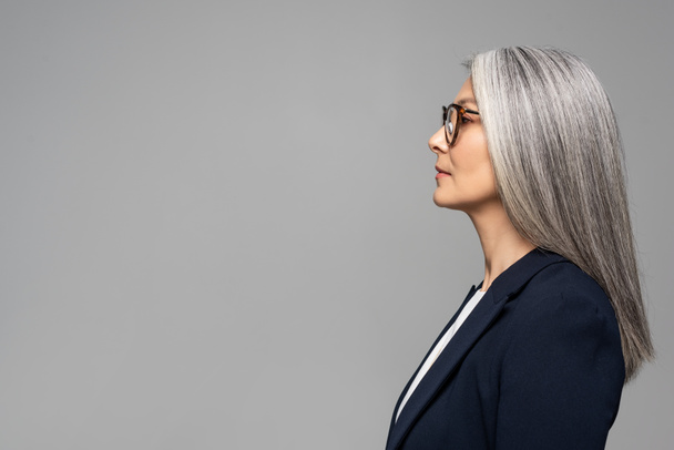 side view of beautiful asian businesswoman with grey hair in eyeglasses isolated on grey - Fotoğraf, Görsel