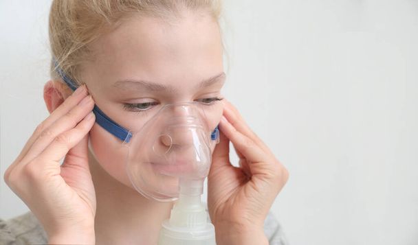 Girl with asthma inhaler. Girl with asthma or allergy problems making inhalation with mask on her face. - Foto, imagen