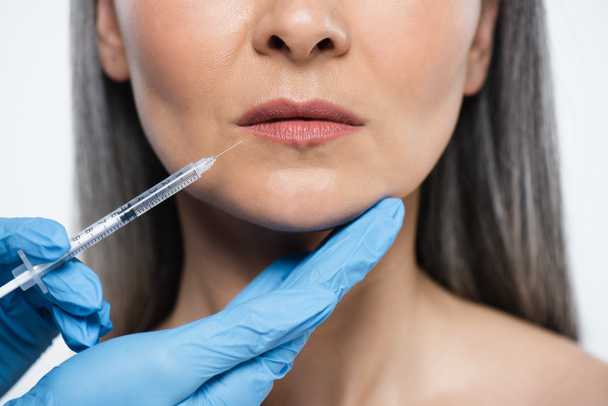 cropped view of naked adult woman and doctor in latex gloves holding syringe with beauty injection isolated on grey - Foto, Imagem