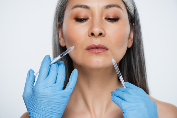 beautiful nude asian woman and doctors in latex gloves holding syringes with beauty injections isolated on grey - Fotografie, Obrázek