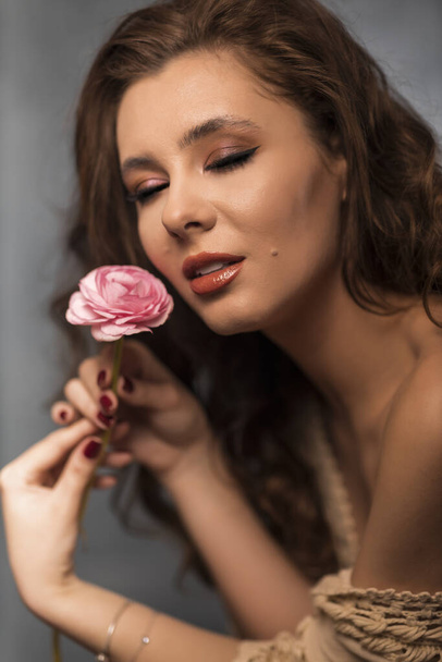 Portrait of young woman with beautiful professional makeup and flower on grey background - Fotografie, Obrázek