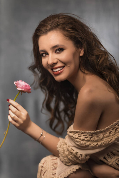 Retrato de mujer joven con hermoso maquillaje profesional y flor sobre fondo gris
 - Foto, imagen