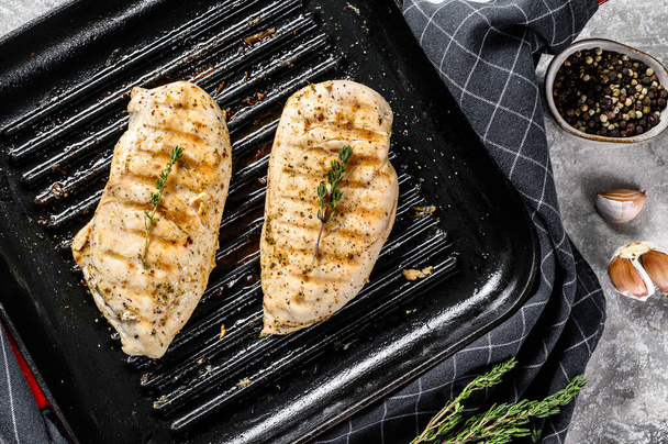 grilled chicken breast in a pan with thyme and garlic. gray background. Top view. - Fotó, kép