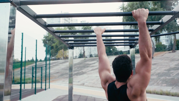 Back view of sportsman training on climbing frame on street - 映像、動画