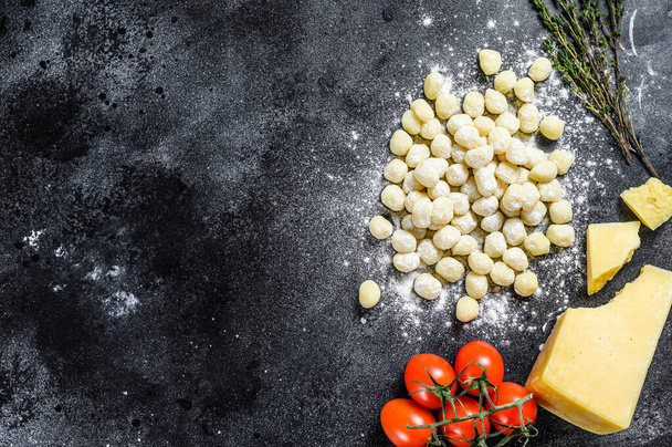 Házi készítésű, főzés nélküli burgonya gnocchi tésztafőzéshez szükséges összetevőkkel. Fekete háttér. Első látásra. Fénymásolási hely. - Fotó, kép