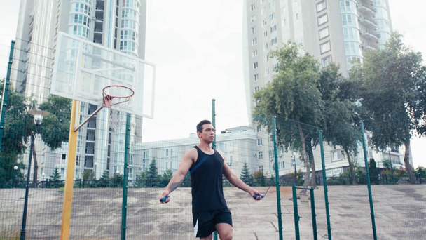 Низький кут зору спортсмен стрибає з пропускаючою мотузкою біля баскетбольного кільця
  - Кадри, відео
