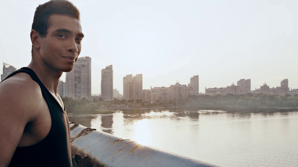 Sportler lächelt und blickt auf Brücke in die Kamera - Filmmaterial, Video
