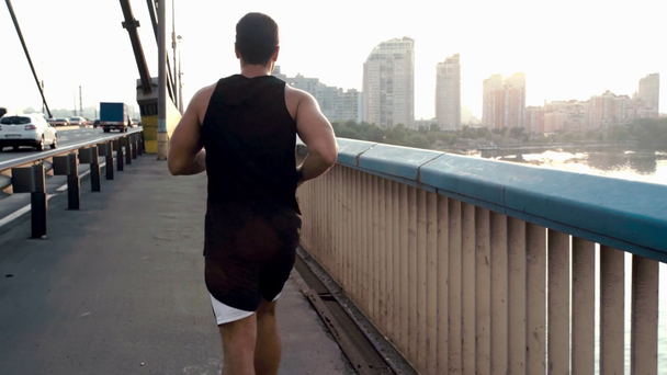 Vista trasera del deportista corriendo en el puente en la calle
 - Imágenes, Vídeo