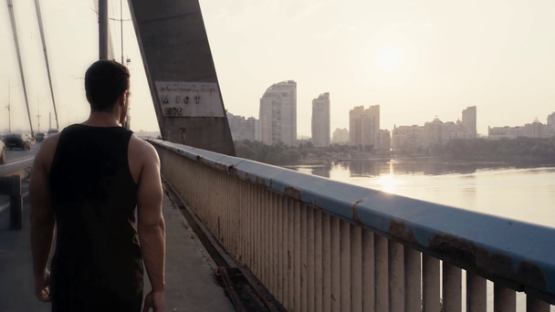 Pohled zezadu na sportovce kráčejícího po mostě  - Záběry, video