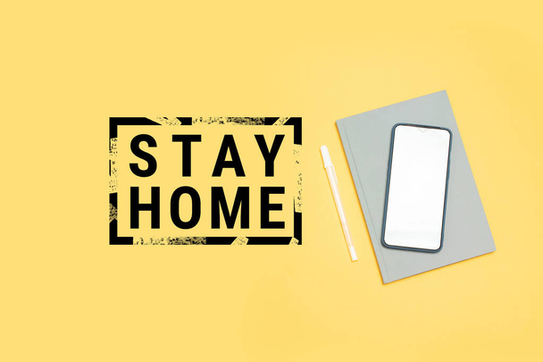 Restez à la maison concept de travail. Carnet et smartphone sur fond jaune, vue de dessus
 - Photo, image