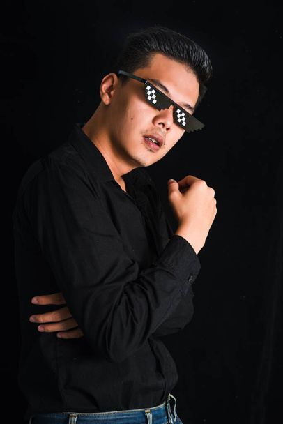 Handsome young man in black shirt keeping arms crossed wear glasses on black background , Asia Portrait - Photo, Image