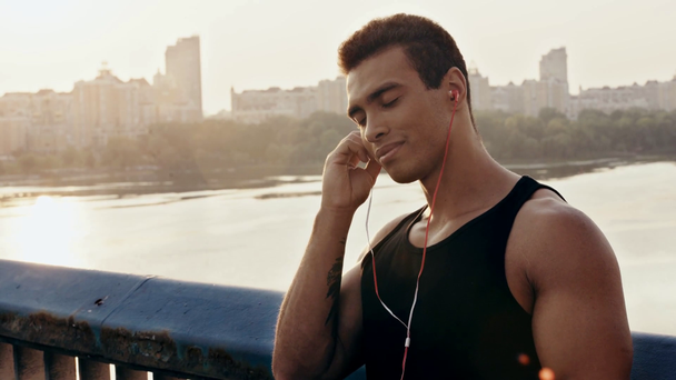 Sportsman souriant et mettant des écouteurs dans les oreilles sur le pont
 - Séquence, vidéo
