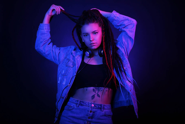 Sexy portrait of a young woman, in neon pink and blue light. Girl with dreadlocks in a nightclub, shining make-up with highlighter. Dance in the club. Glitter skin.Clubber, night life concept - Foto, imagen