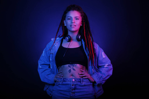 Sexy portrait of a young woman, in neon pink and blue light. Girl with dreadlocks in a nightclub, shining make-up with highlighter. Glitter skin. Clubber, night life concept - Foto, imagen