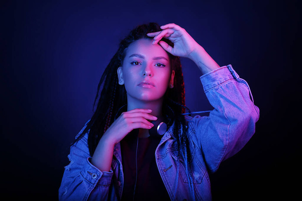 Sexy portrait of a young woman, in neon pink and blue light. Girl with dreadlocks in a nightclub, shining make-up with highlighter. Glitter skin. Clubber, night life concept - Фото, изображение