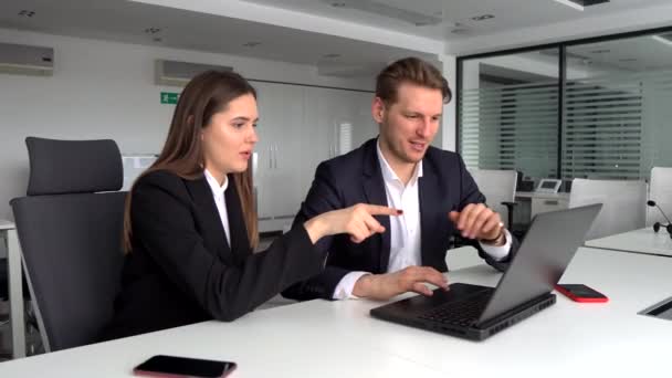 business colleagues sitting at a table in a modern office, talking together over a laptop - Footage, Video