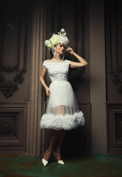 beautiful bride in a white dress, hat and earrings, beauty and youth, happiness and innocence - Fotó, kép