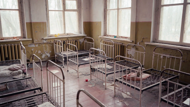 Abandoned room in kindergarten with metal beds, papers and toy in Chernobyl, Ukraine - Filmmaterial, Video