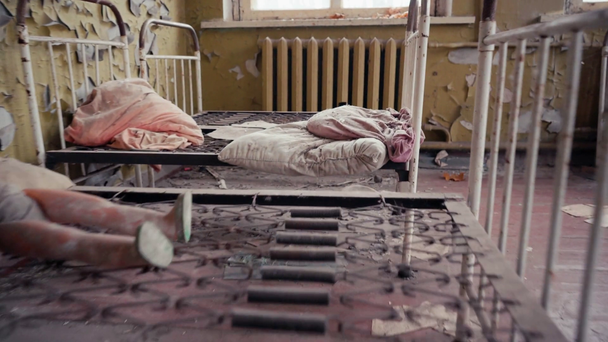 Εγκαταλελειμμένα μεταλλικά κρεβάτια με χαρτιά, παιχνίδια και κλινοσκεπάσματα στο νηπιαγωγείο του Τσερνομπίλ, Ουκρανία - Πλάνα, βίντεο
