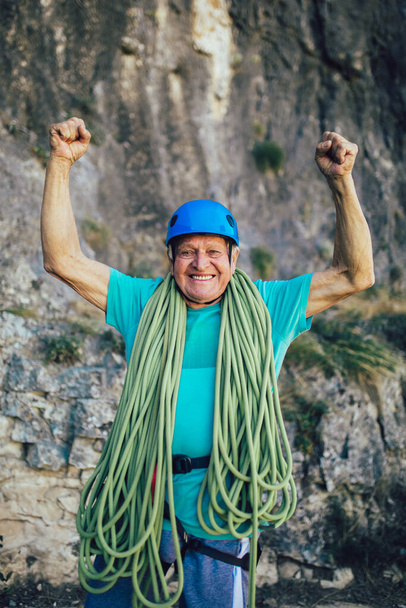 Idősebb ember kötéllel, aki felkészül a sziklamászásra.. - Fotó, kép
